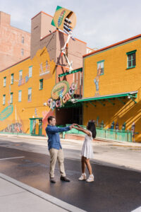 A joyful and spontaneous moment shared outside a whimsical yellow and green mural.