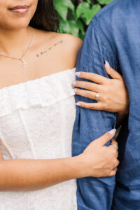 Detailed shot of the woman’s engagement ring and tattoo reading "I choose you always" as she holds her partner’s arm.