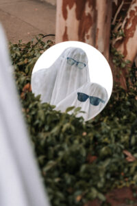 A ghost costume close-up shows the couple's reflection in a circular mirror.
