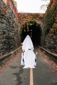 A couple dressed as ghosts stands outside the tunnel with arms raised playfully in peace signs.